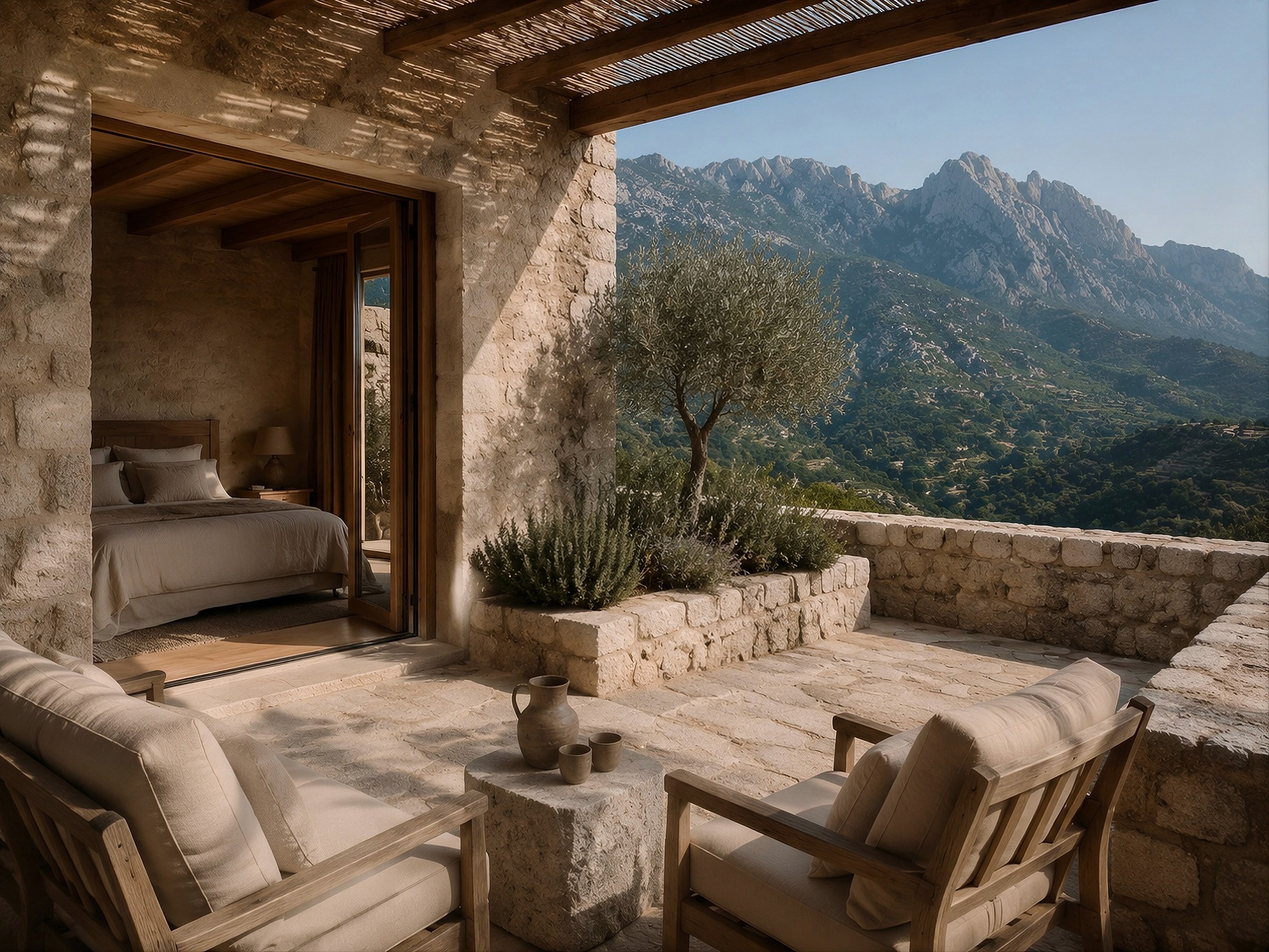 A shaded stone terrace with lounge seating outside a bedroom, offering a scenic view of a mountainous valley.