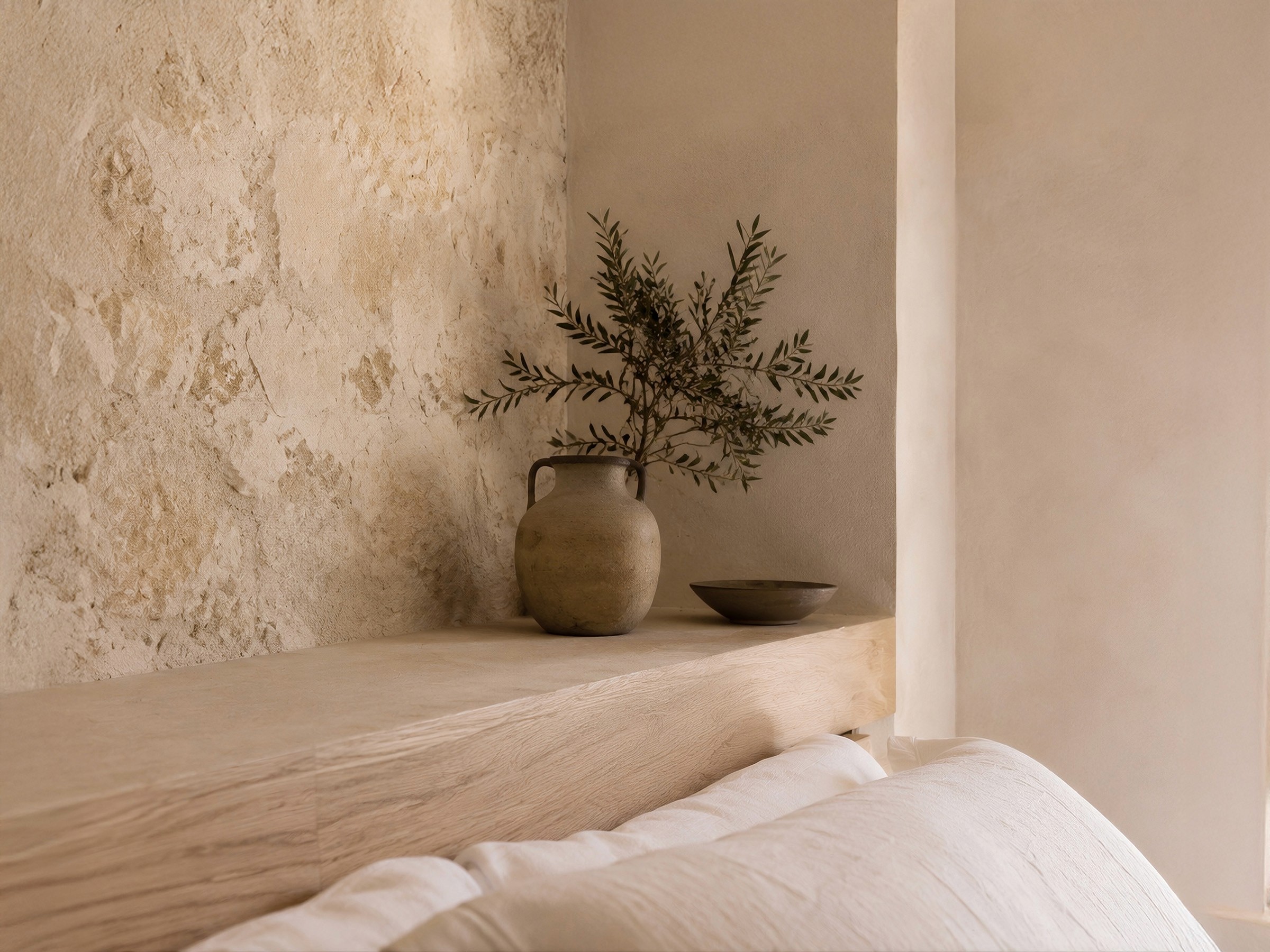 Close-up of a wooden headboard shelf against a stone wall, styled with a rustic vase and olive branches.