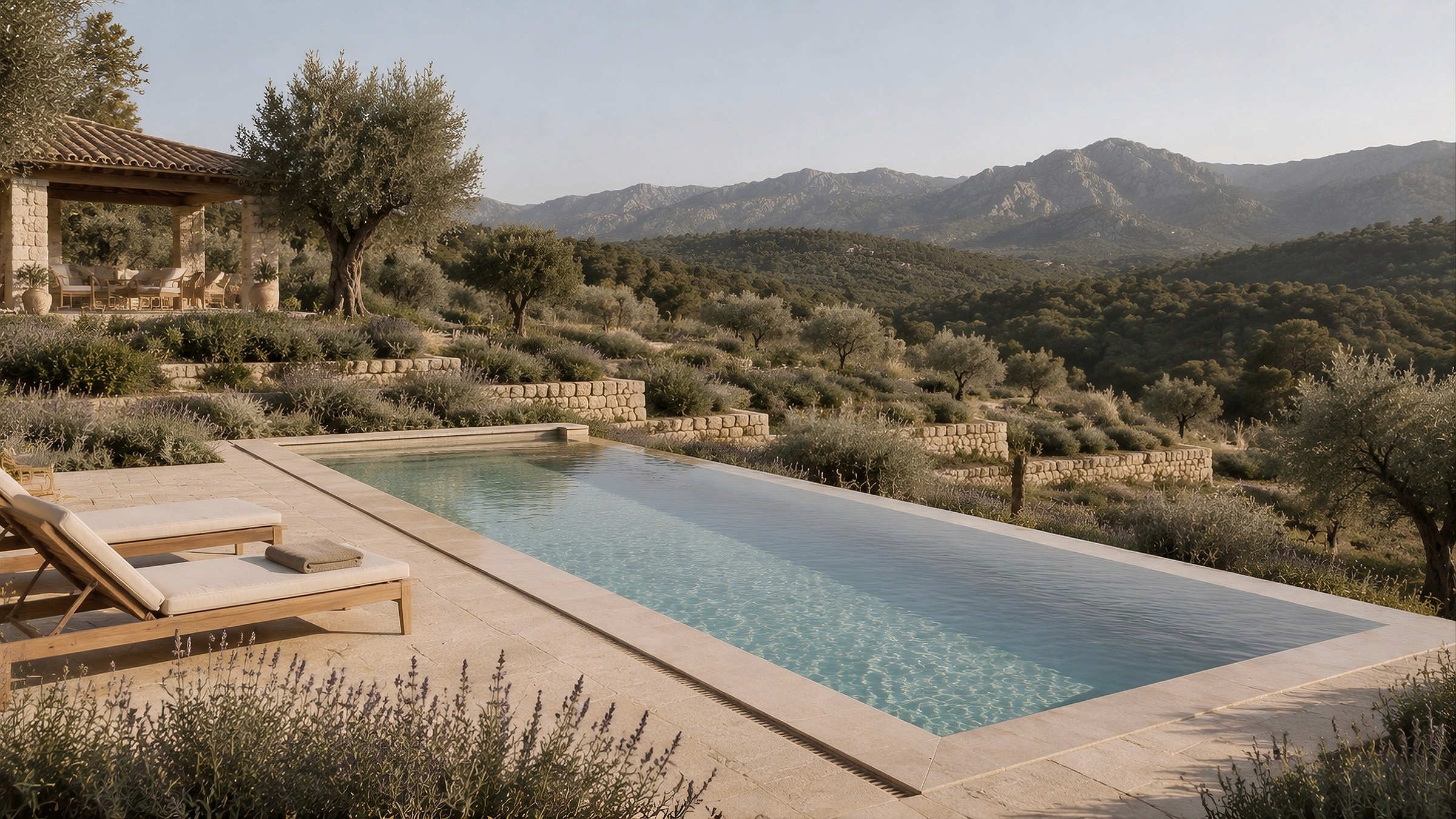 A swimming pool on a terraced stone patio surrounded by lavender, overlooking rolling hills.