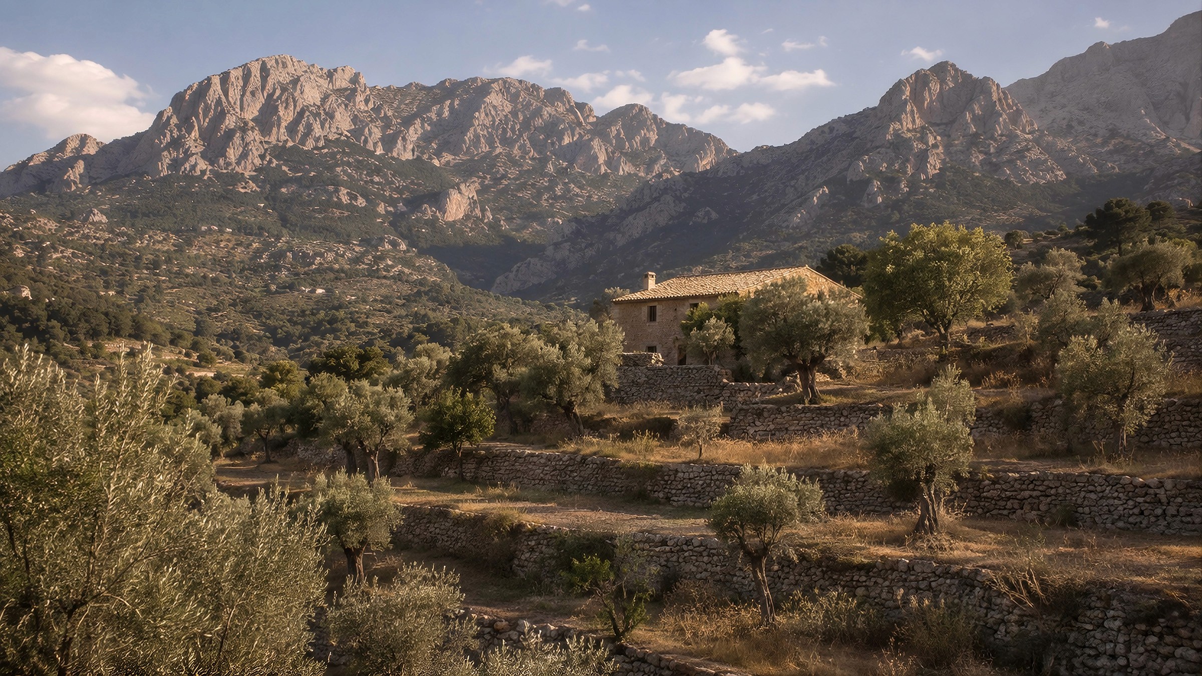 Rustic stone house situated among terraced olive groves beneath dramatic, rocky mountains.